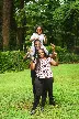 a man and two women holding a child on their shoulders